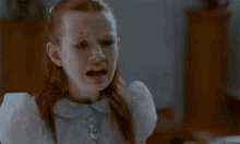 a little girl with red hair is crying in a room with her mouth open .
