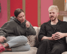 a man and a woman sit on a couch talking
