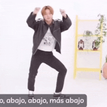 a man in a black jacket and black pants is dancing in front of a yellow ladder