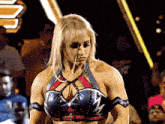 a woman in a wrestling outfit stands in front of a crowd