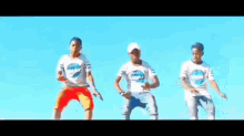 three men are dancing in front of a blue sky .