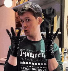 a man wearing black gloves and a sweater that says leigh on boys