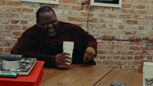 a man sitting at a table with a cup that says purple stop on it