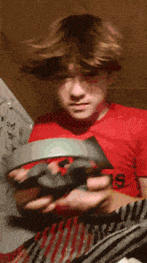 a young boy wearing a red adidas shirt is holding something