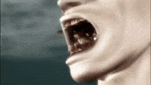 a close up of a person 's face with their mouth open and a worm coming out of it .