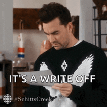a man holding a piece of paper with the words it 's a write off on it