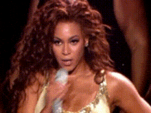 a woman with long curly hair is holding a microphone in her hand .