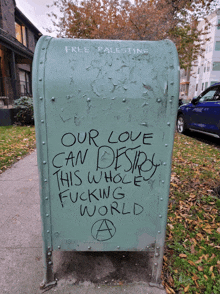 a green mailbox with graffiti on it that says our love can destroy this whole fucking world