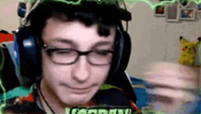 a young man wearing headphones and glasses is smiling while playing a video game .