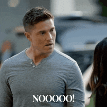 a man in a grey shirt is standing next to a woman and says nooooo