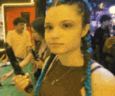 a woman with blue braids is holding a gun in her right hand