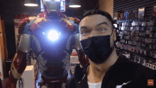 a man wearing a mask is standing in front of a statue of iron man