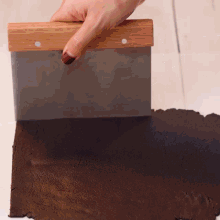 a person is using a spatula to spread a piece of brown dough