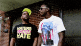 a man wearing a shirt that says haters gonna hate stands next to another man