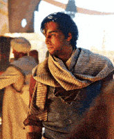 a man wearing a scarf around his neck is standing in a room