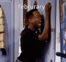 a man is laughing while leaning against a door with the word february written on the door .