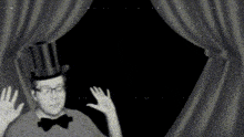 a man in a top hat and bow tie is waving