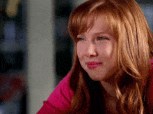 a young girl with red hair and blue eyes looks down
