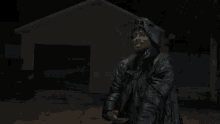 a man wearing a mask and a jacket is standing in front of a garage door