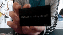 a person is holding a black card that says what is a hydra