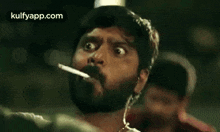 a man with a beard is smoking a cigarette and making a face .