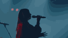 a woman singing into a microphone with a blue background