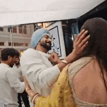 a man in a turban is being kissed by a woman .