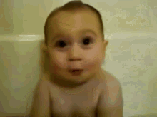 a baby is sitting in a bathtub making a funny face .