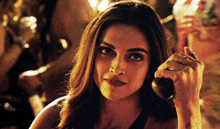 a woman is talking on a cell phone with a crowd in the background