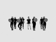 a group of women are dancing in a black and white photo with shields .