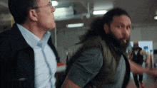 a man with a beard is standing next to another man .
