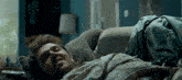 a man laying on a couch with his eyes closed and a remote control in front of him