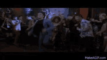a group of people are dancing in a dark room with the website makeagif.com in the corner