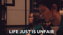 a man and a woman sit next to each other with the words life just is unfair