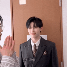 a man in a suit and tie is standing in front of a door