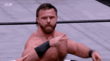 a man with a beard is sitting in a wrestling ring and pointing at the camera .
