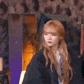 a woman with long blonde hair is wearing a black jacket and a blue shirt .