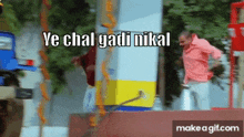 a man in a pink shirt is standing next to a yellow and blue pole with the words ye chal yadi nikal on it