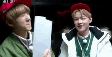 two young men are standing next to each other and one of them is holding a piece of paper in his hand .