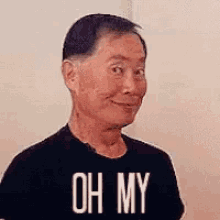 a man wearing a black t-shirt with the words `` oh my '' on it is smiling .