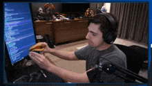 a man wearing headphones holds a hamburger in front of a computer monitor