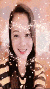 a woman in a striped shirt is smiling with sparkles coming out of her eyes