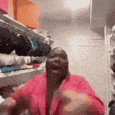 a man in a pink robe is standing in front of a closet filled with clothes .