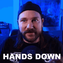 a man with long hair and a beard is wearing a hat and a shirt that says hands down