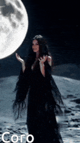 a woman in a black dress stands in front of a full moon