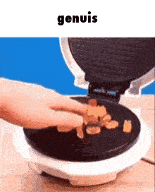 a person is putting food into a waffle maker and the word genuis is above it