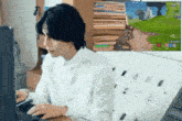 a man in a white shirt is sitting at a desk playing a video game .