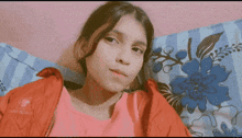 a young girl wearing a red jacket is laying on a bed