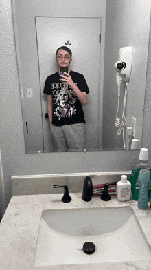 a man taking a picture of himself in a bathroom mirror wearing a shirt that says beetlejuice