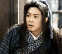 a man with long hair and a scarf on his head is wearing a costume and making a funny face .